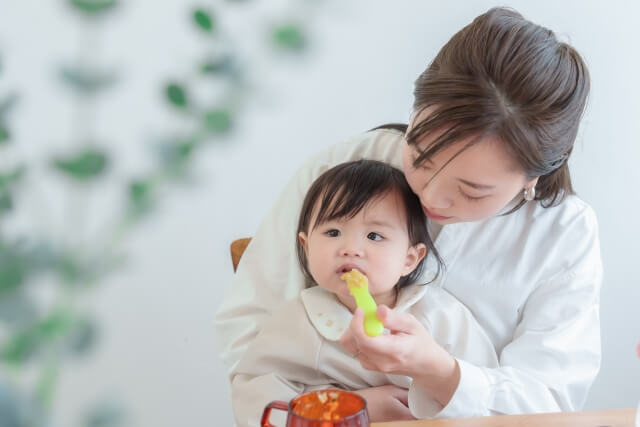 離乳食を食べさせる母